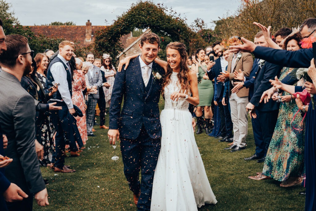 Bride and groom walking through a shower of confetti at a wedding in East Sussex