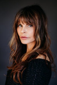 A close up of a beautiful woman's face, she has long wavy dark hair.
